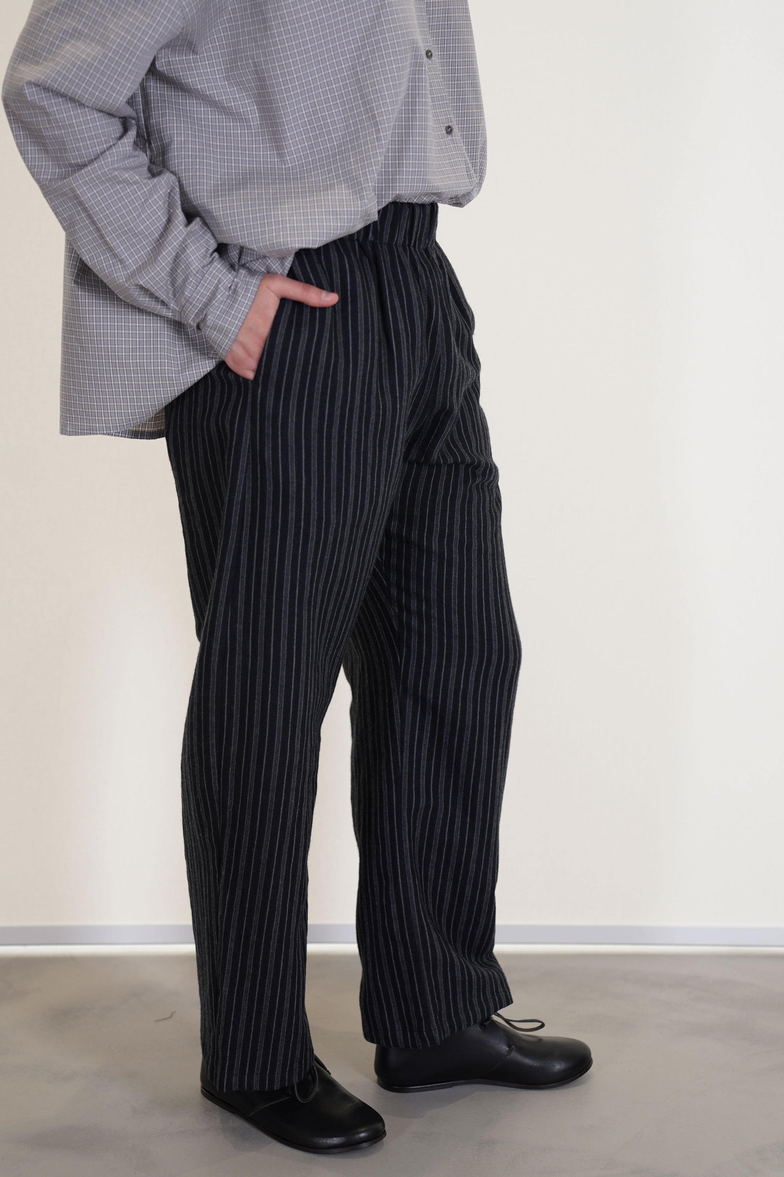 side view of apuntob (a.b) trousers stripes black relaxed fit, long curved leg