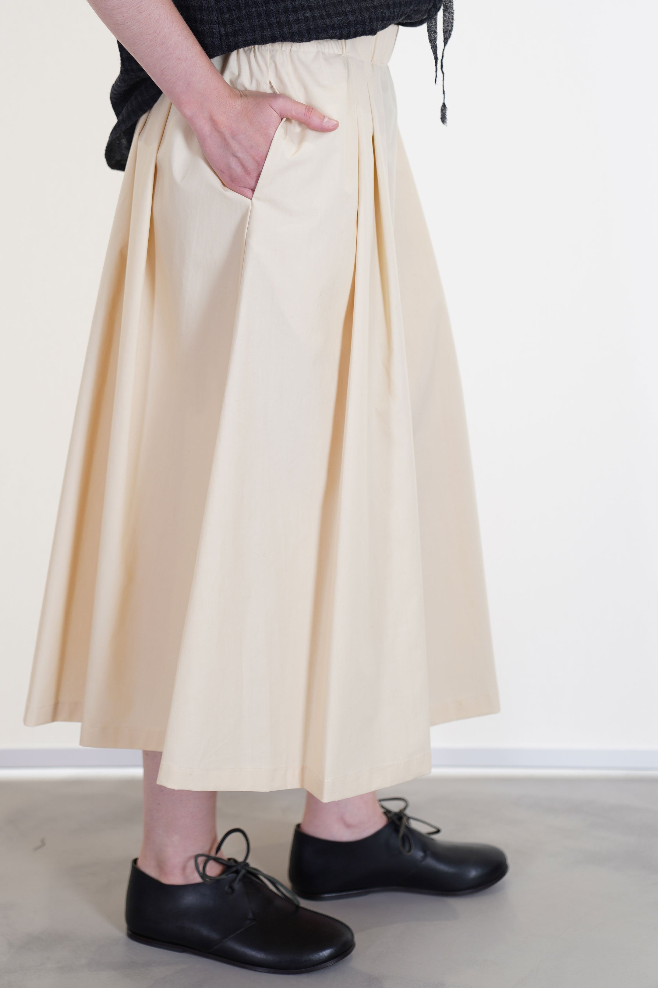 side view of apuntob (a.b) skirt natural midi length and side pockets. unlined.