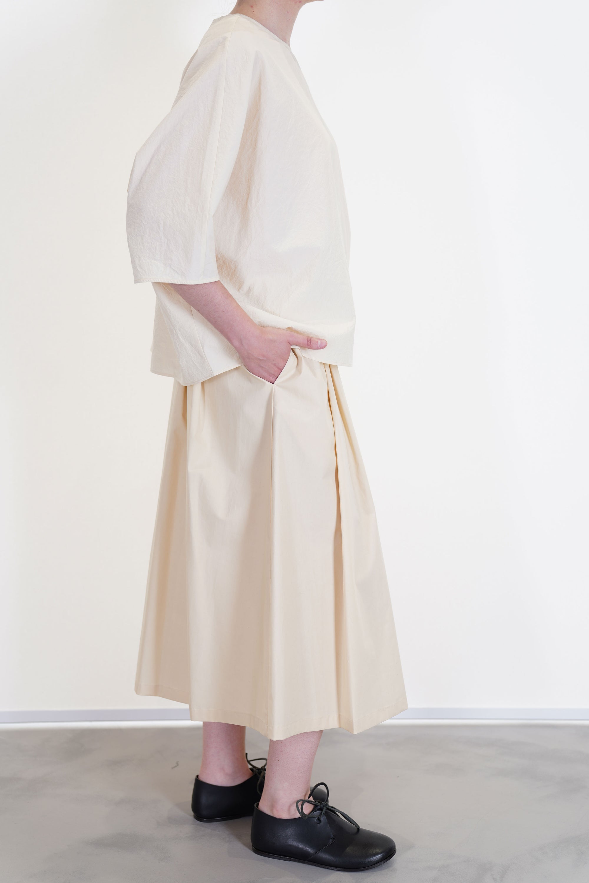 side view of apuntob (a.b) skirt natural worn with shirt natural for a monochrome and soft look