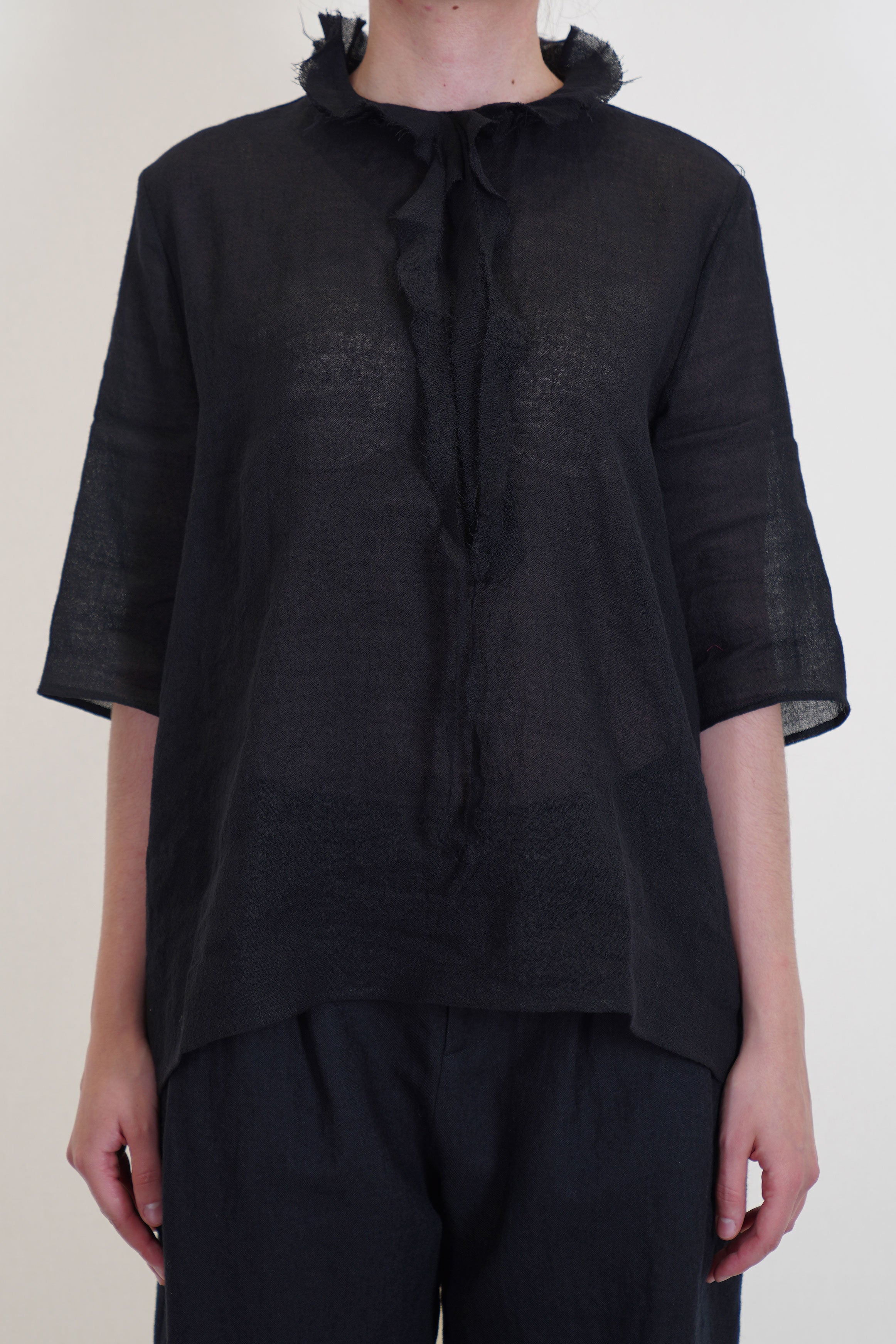 apuntob (a.b) shirt black featuring ruffle details at the neckline, elbow length slim sleeves and a fitted cut on the shoulders.