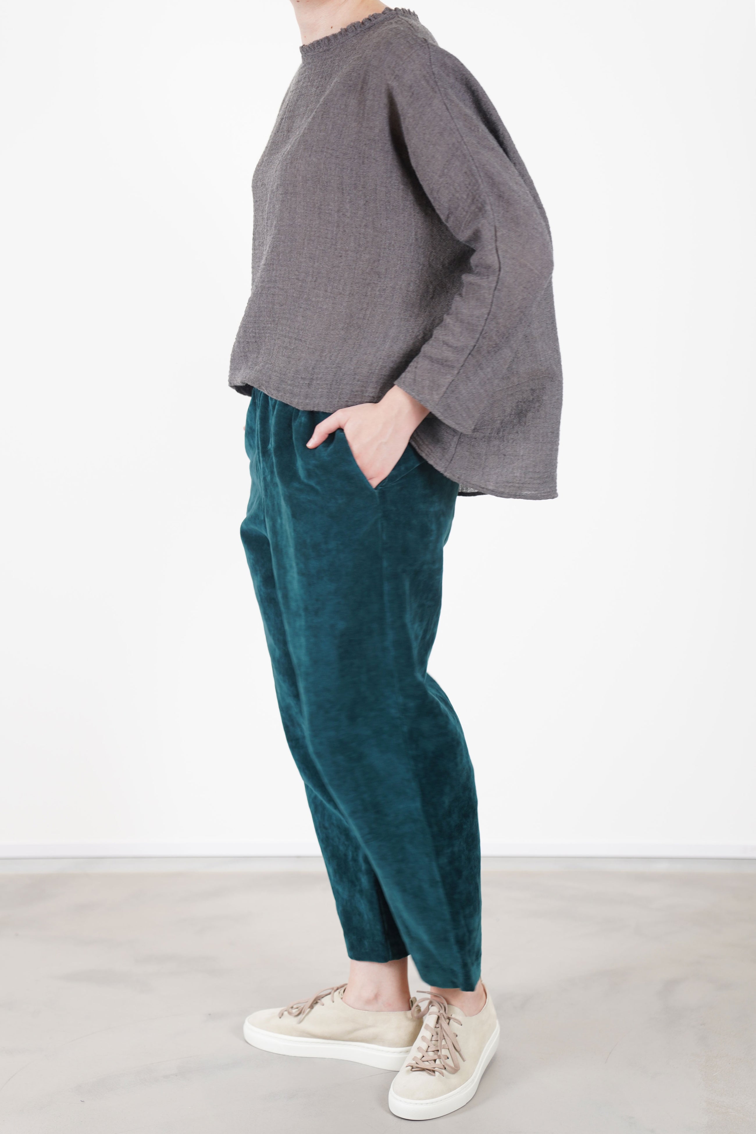 side view of apuntob (a.b) velvet trousers peacock blue featuring practical side seam pockets for added functionality