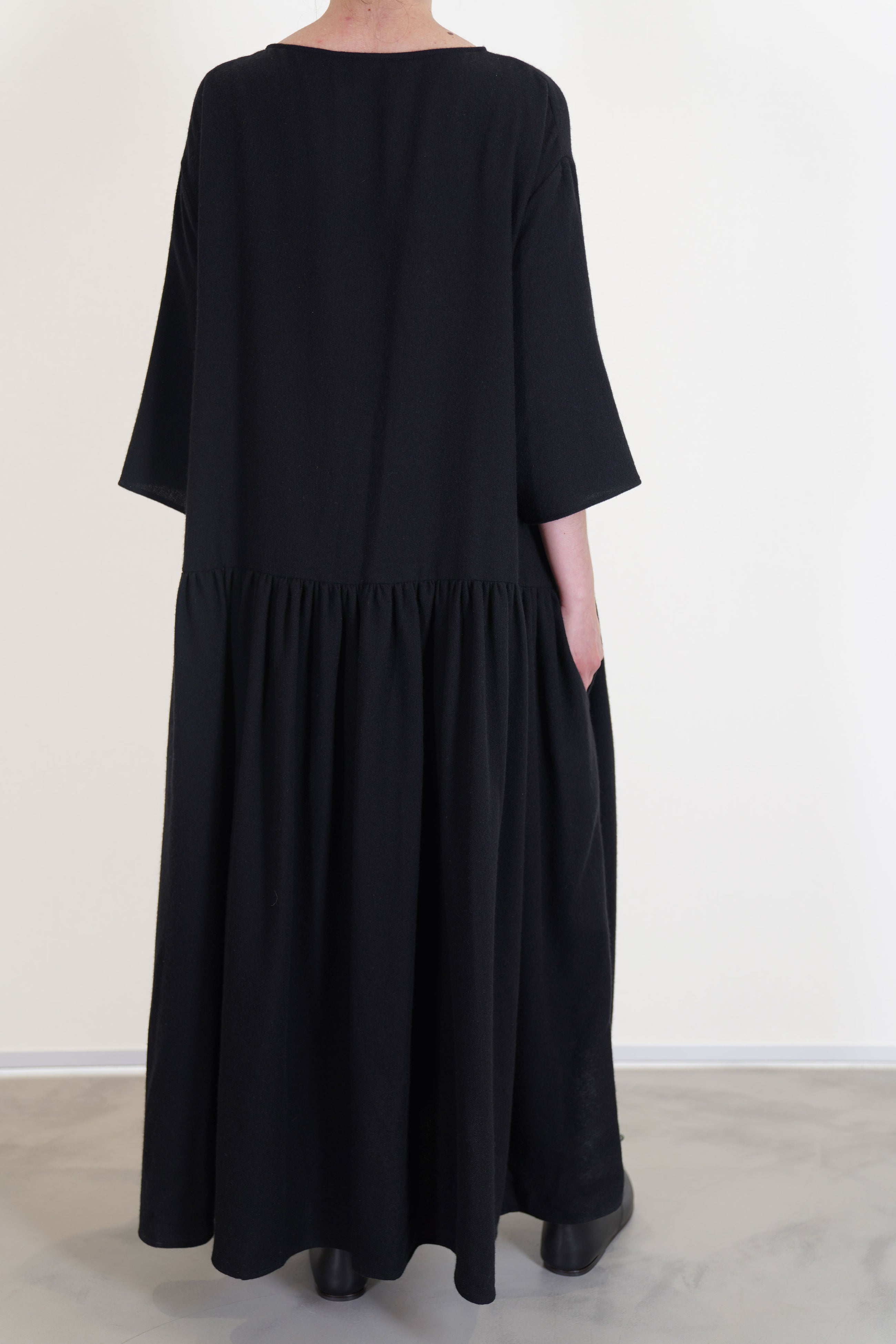 back view of apuntob (a.b) dress black drop shoulders with elbow length sleeves and side pockets.
