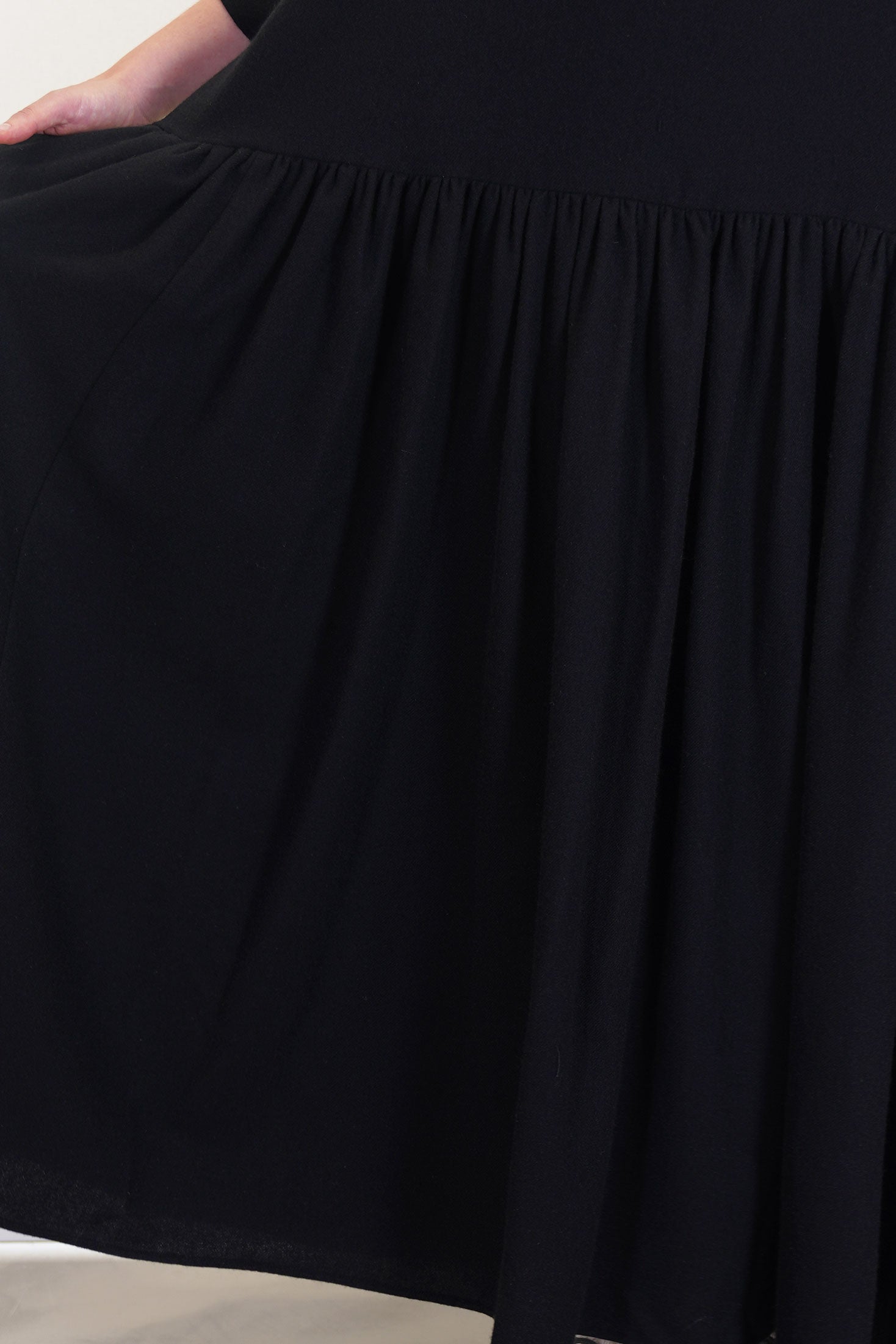 detail view of apuntob (a.b) dress black luxurious cashmere material. gathered material along the waistline and pleated details at the skirt