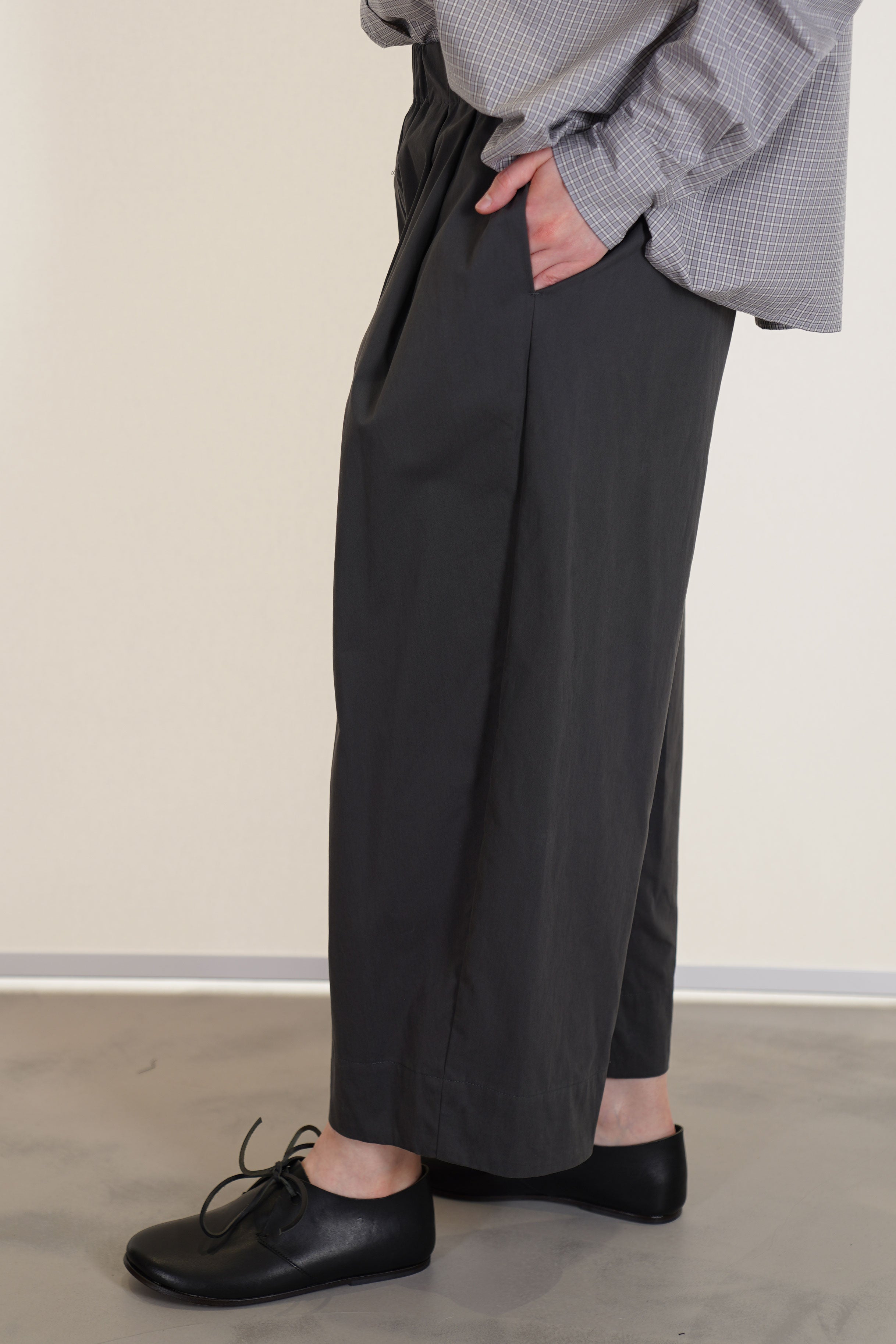 side view of apuntob (a.b) trousers stone featuring a cropped length, an elasticated wasitband