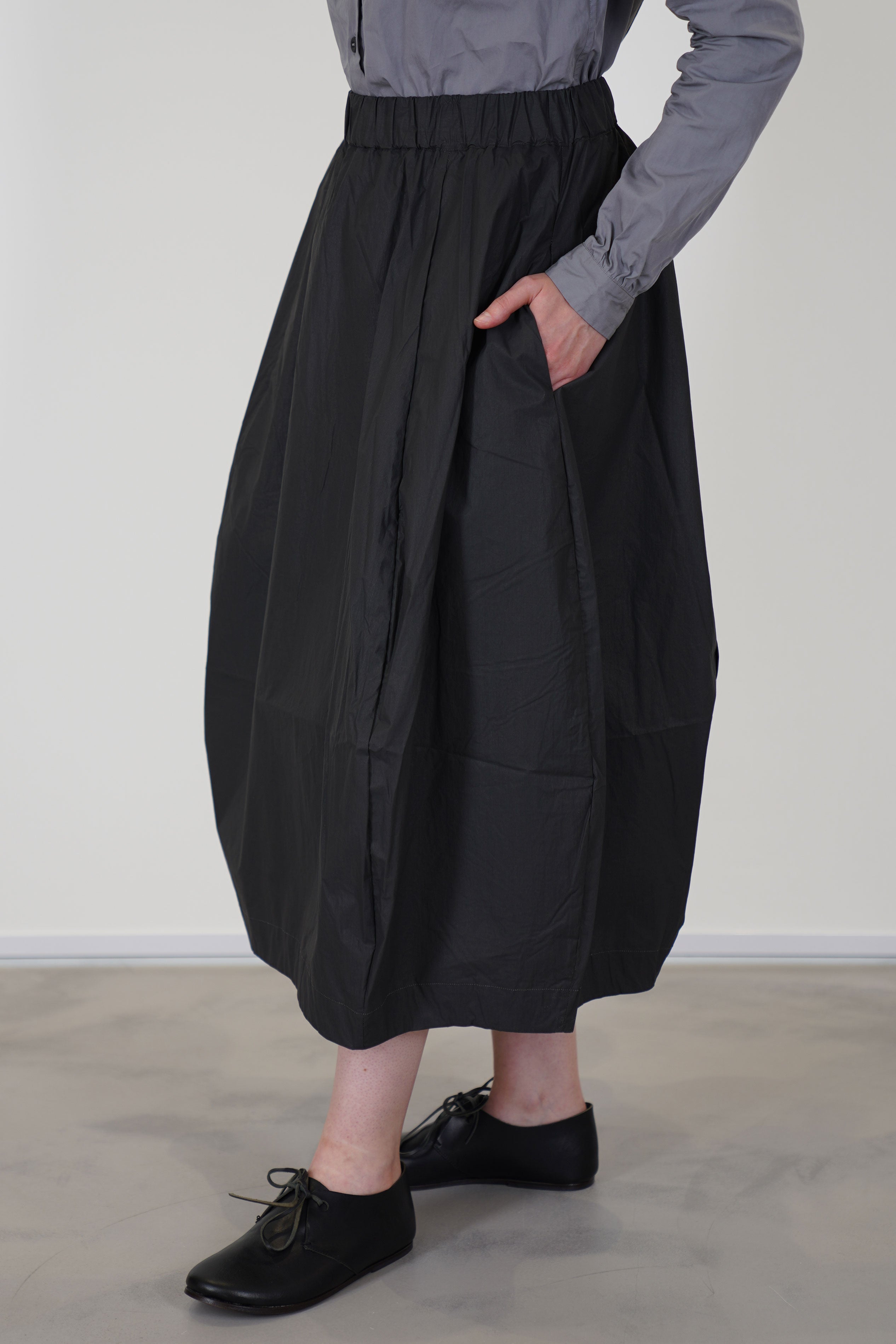 detail view of bergfabel coated cotton carla skirt carbon side pocket details and midi length