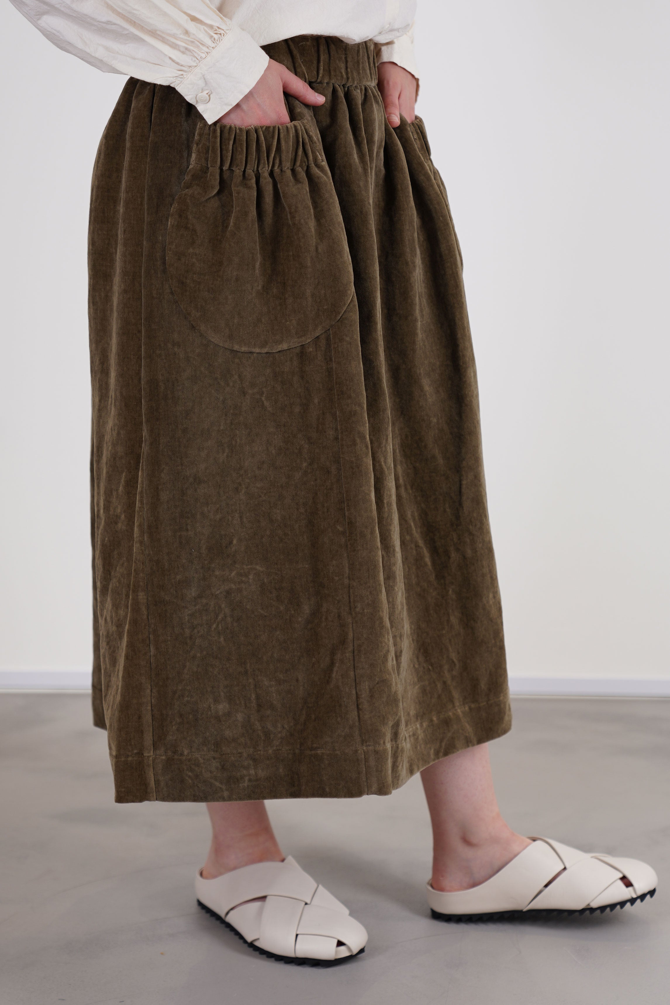 side view of casey casey ghost skirt velvet taupe front slip pockets with an elasticated detail, midi length.