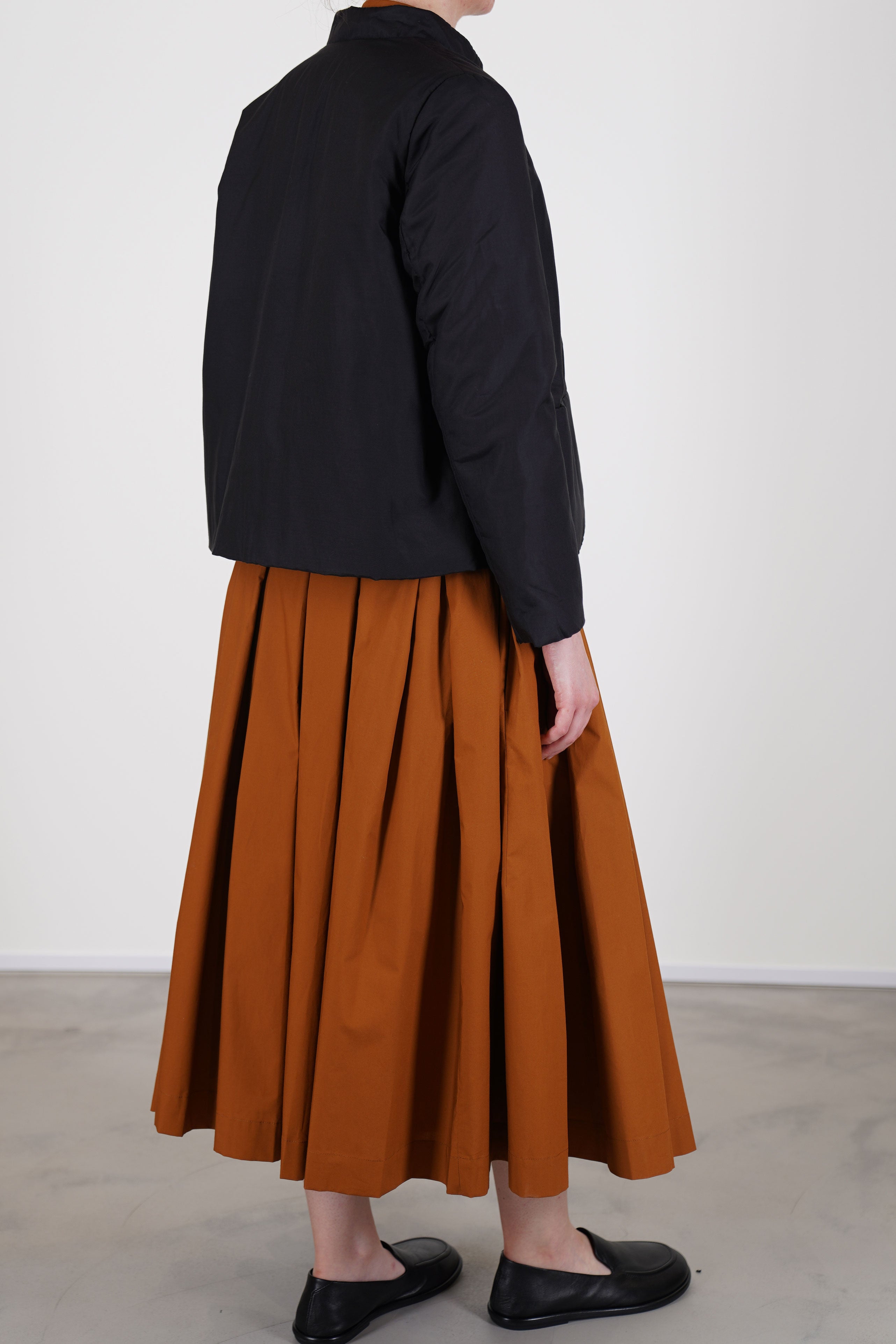 back view of école de curiosités padded jacket jessica silk cotton black worn with skirt solange in caramel brown