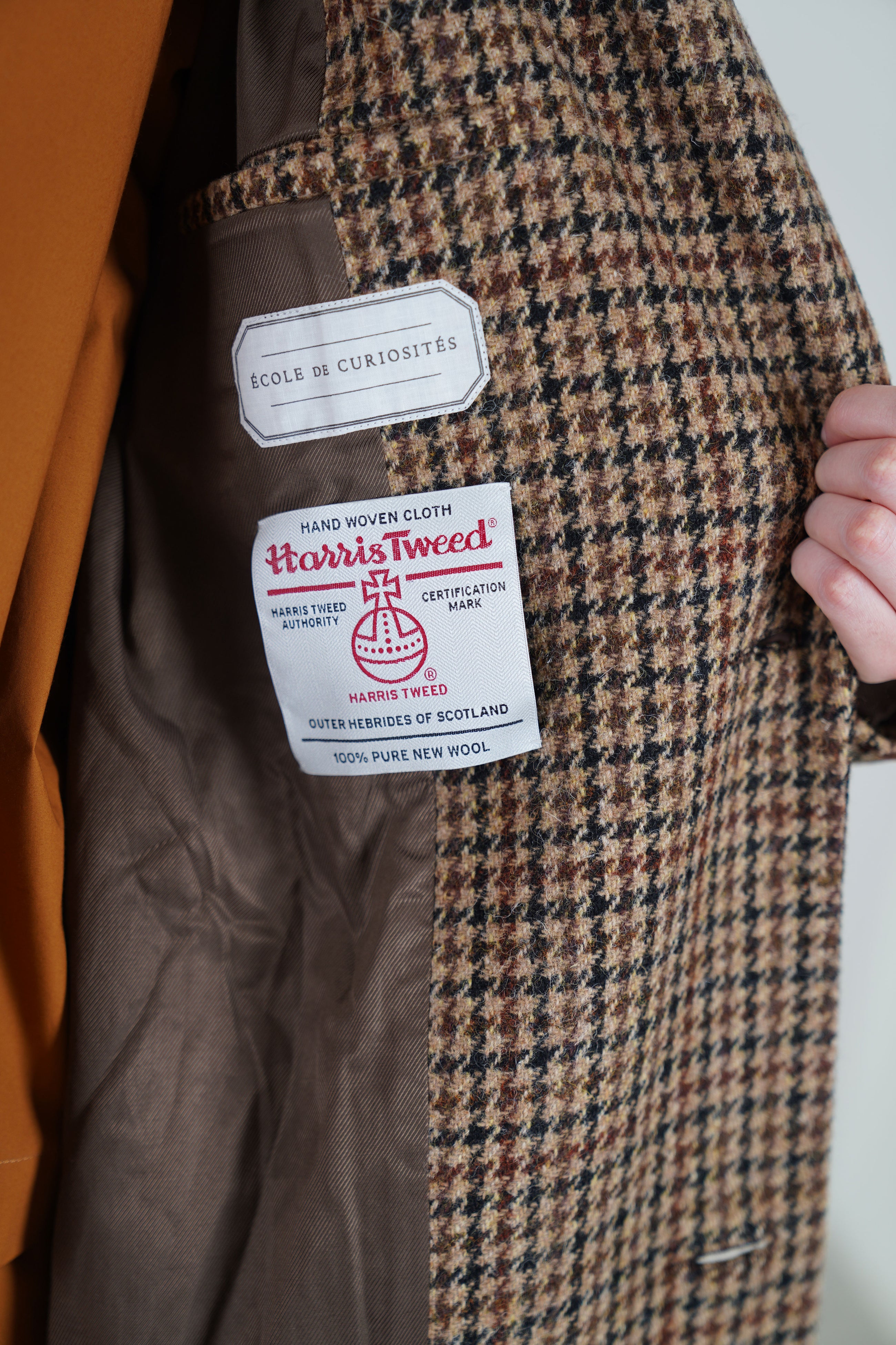 detail view of inside smooth lining and harris tweed certification mark of école de curiosités wool coat coper mix brown tweed