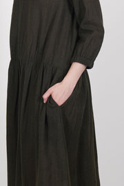 detail view of apuntob (a.b) wool dress in military green featuring elasticated band details at the cuffs, as well as pleated accents at the waist