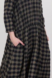 detail view of apuntob (a.b) dress woolen black check dropped shoulders and mid-length sleeves featuring elasticated band details at the cuffs, as well as pleated accents at the waist. 