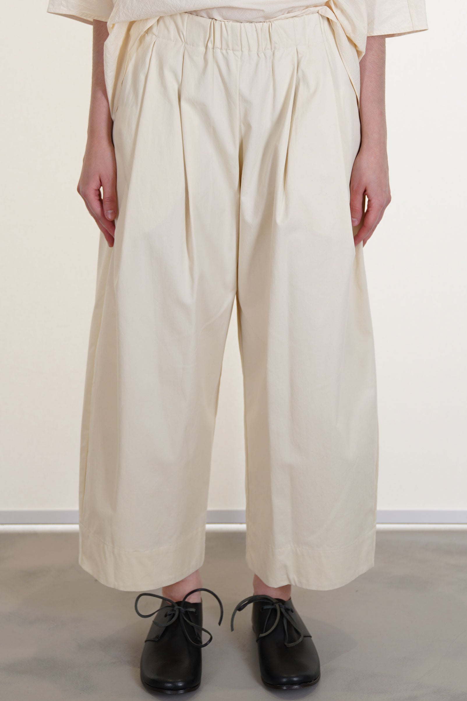 apuntob (a.b) trousers natural featuring a cropped length, wide pleat details at the front and an elasticated wasitband