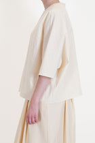 side view of apuntob (a.b) shirt natural elbow length sleeves and drop shoulders in a wide and relaxed fit.