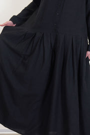detail view of apuntob (a.b) woolen dress black featuring a half panel button front opening and wide pleated details at the skirt