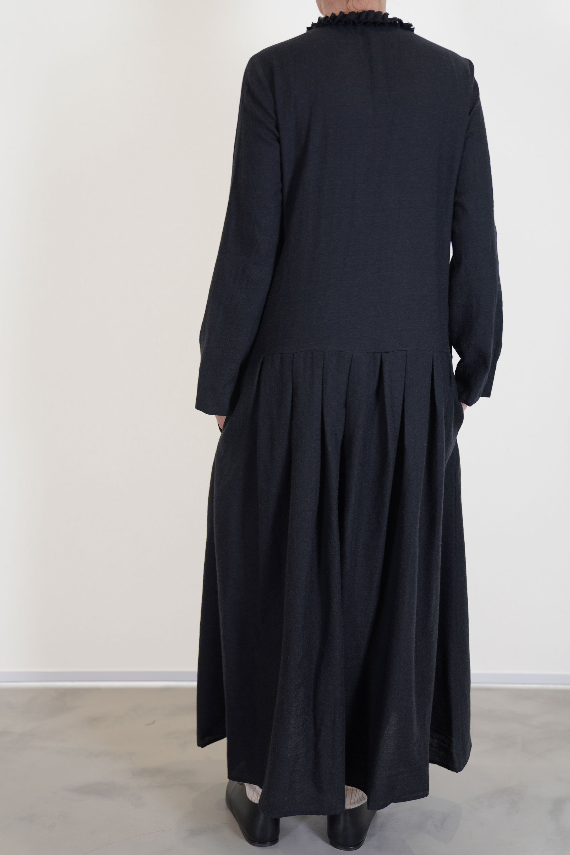 back view of apuntob (a.b) woolen dress black ruffle details at the neckline, long sleeves and a narrow fit on the shoulders. 