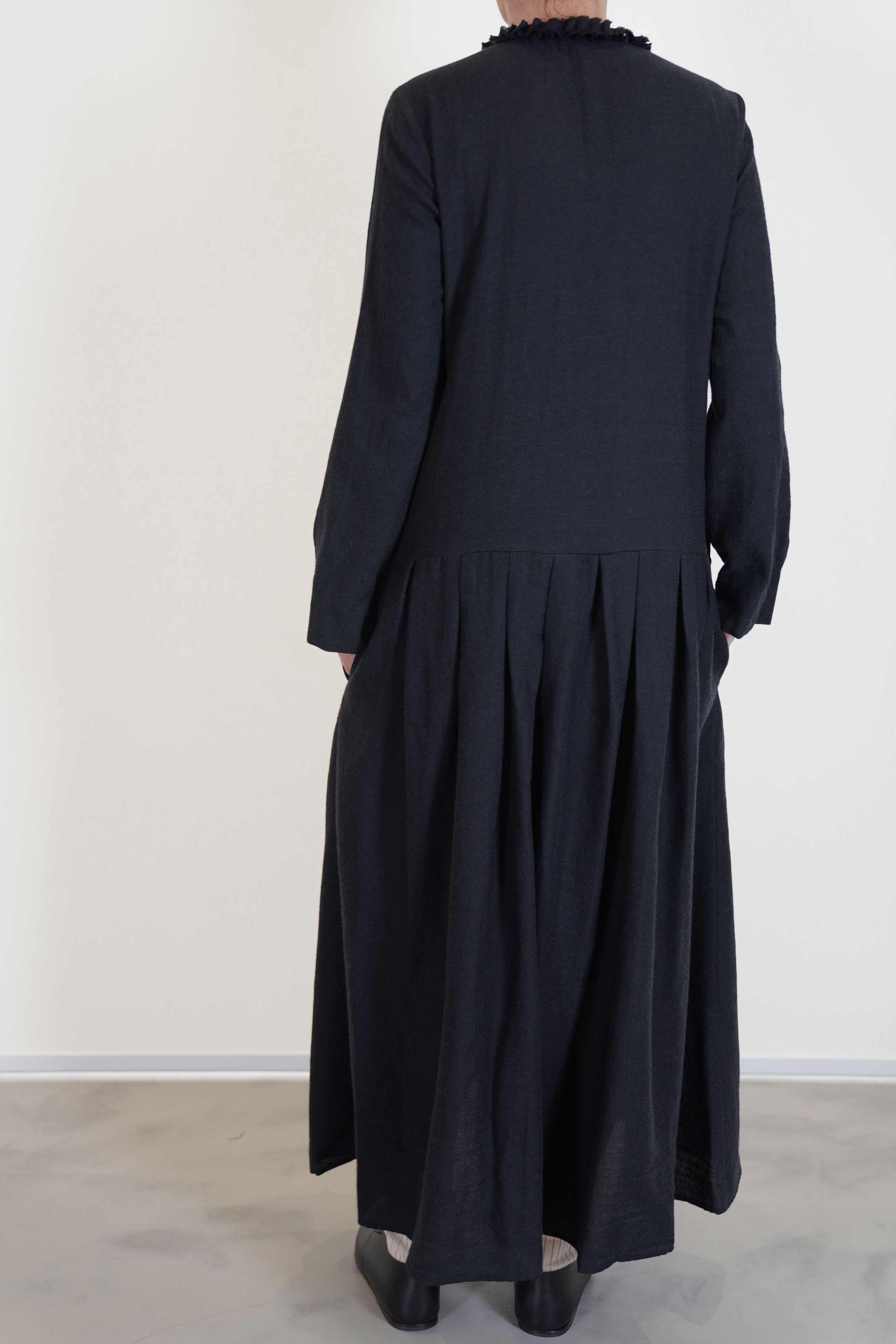 back view of apuntob (a.b) woolen dress black ruffle details at the neckline, long sleeves and a narrow fit on the shoulders. 