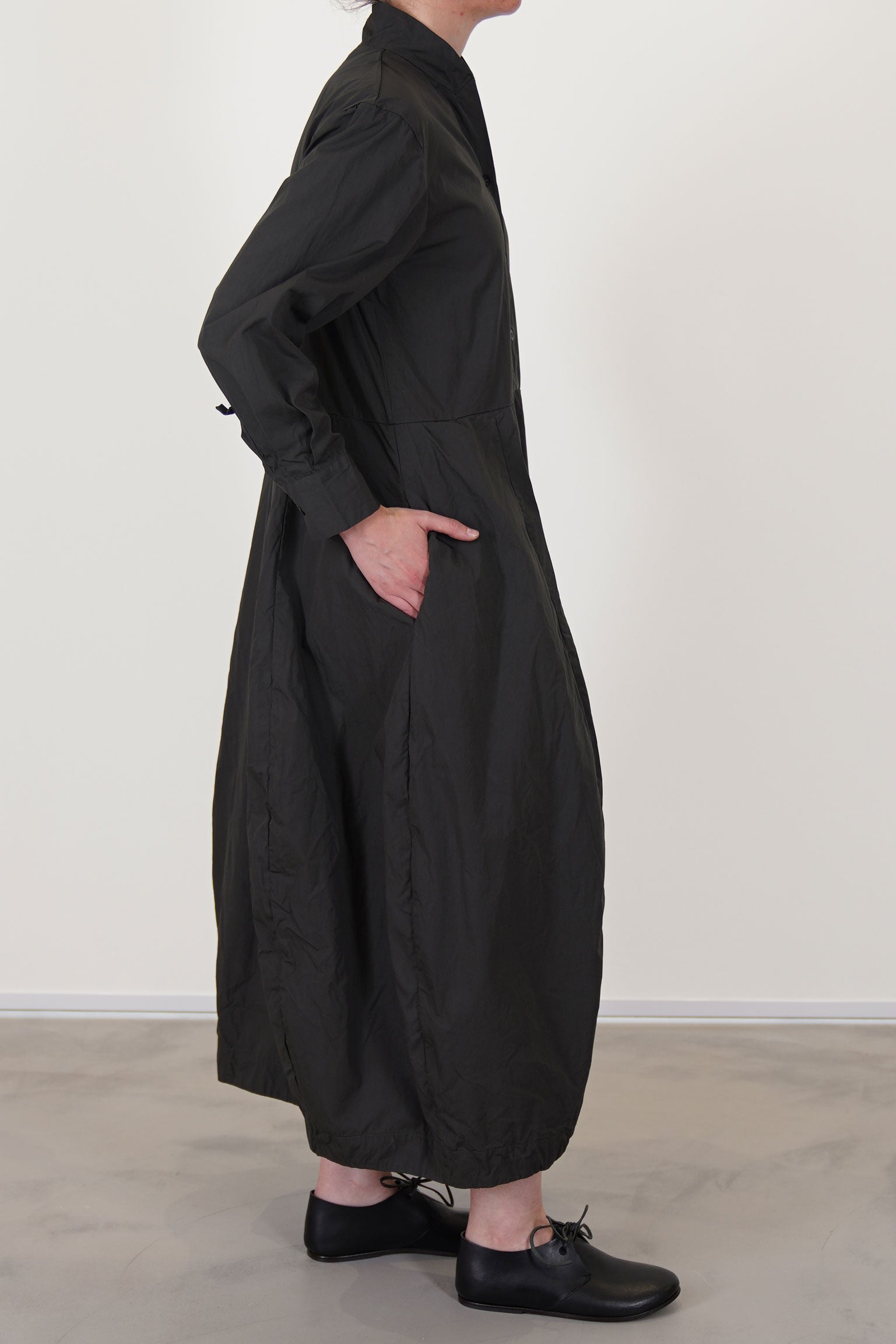 side view of bergfabel letty dress moss  featuring a slimmer fit on the top, slightly raised waist and a balloon style skirt with side pockets