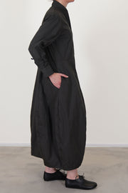 side view of bergfabel letty dress moss  featuring a slimmer fit on the top, slightly raised waist and a balloon style skirt with side pockets