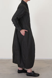 side view of bergfabel letty dress moss  featuring a slimmer fit on the top, slightly raised waist and a balloon style skirt with side pockets