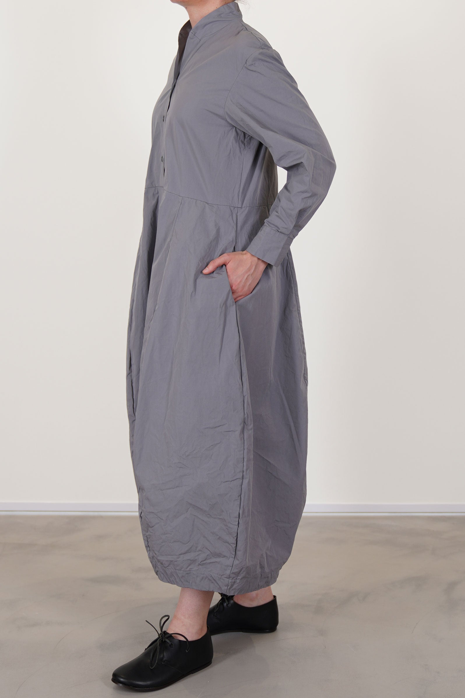 side view of bergfabel letty dress fog featuring a slimmer fit on the top, a half pannel front button opening