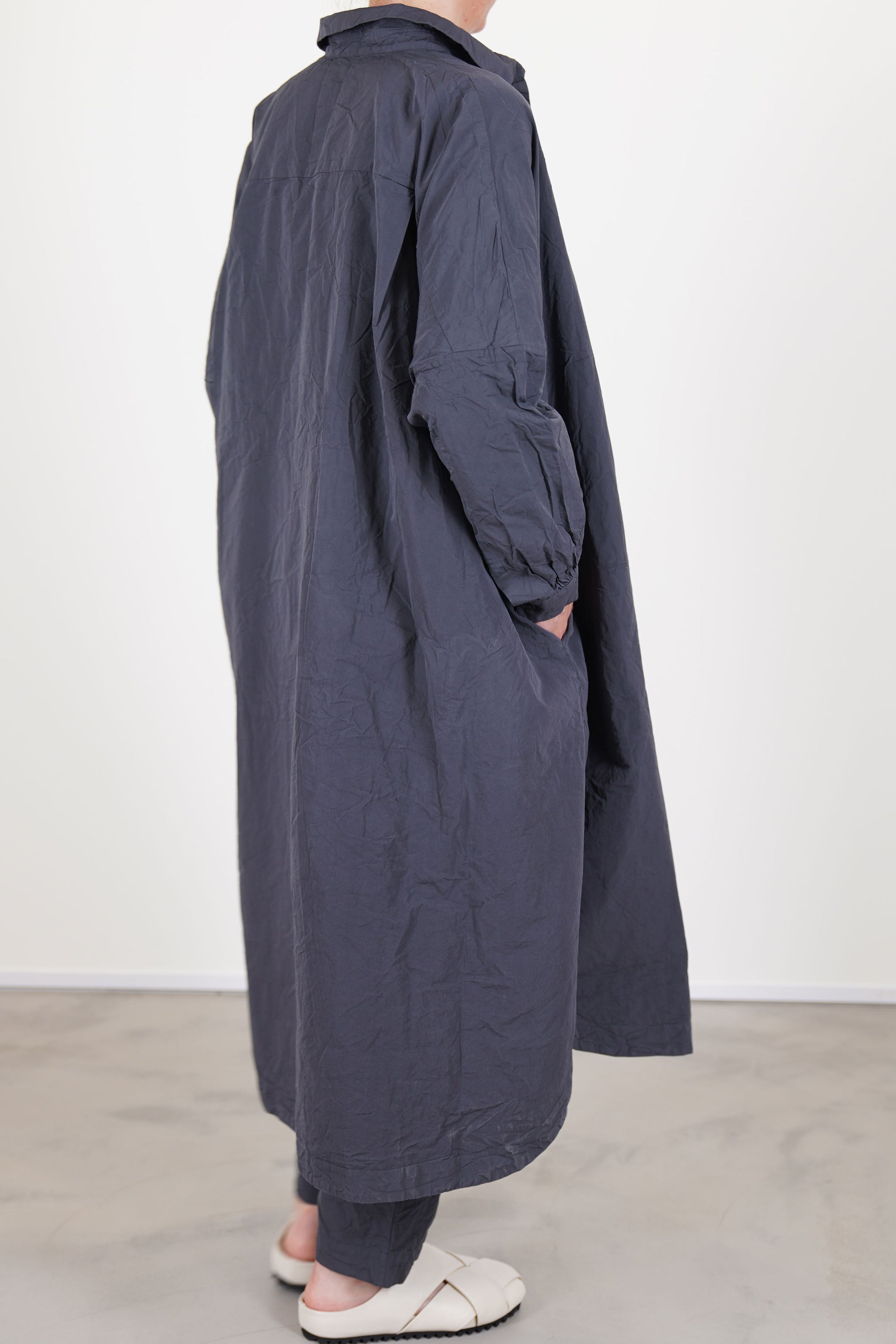 back view of casey casey yuki dress blu skull worn as an overcoat, side pocket details and paired with matching tippy pants