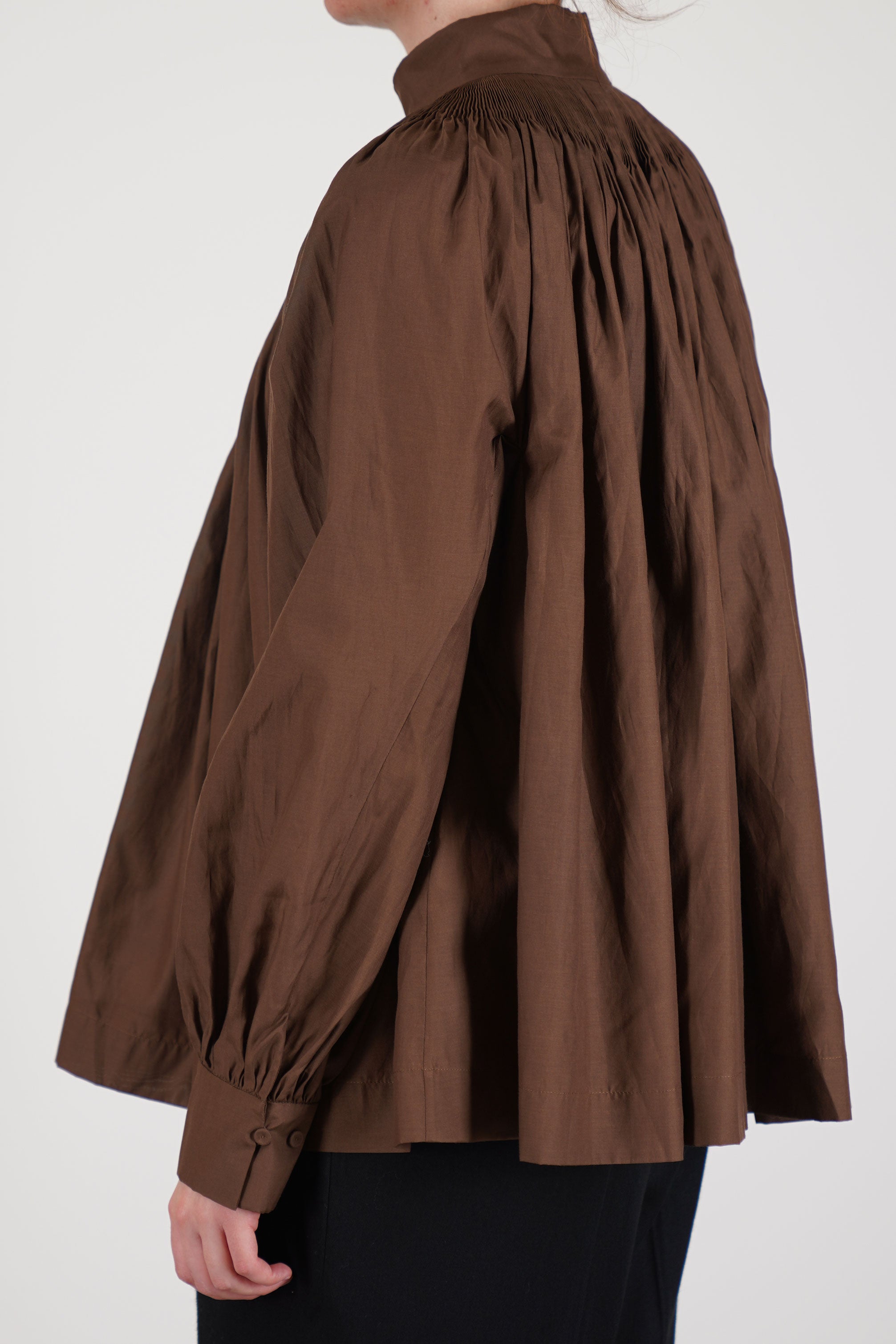 side view of école de curiosités shirt anne cotton silk brown voluminous sleeves narrow into tailored cuffs, creating a harmonious shape. 