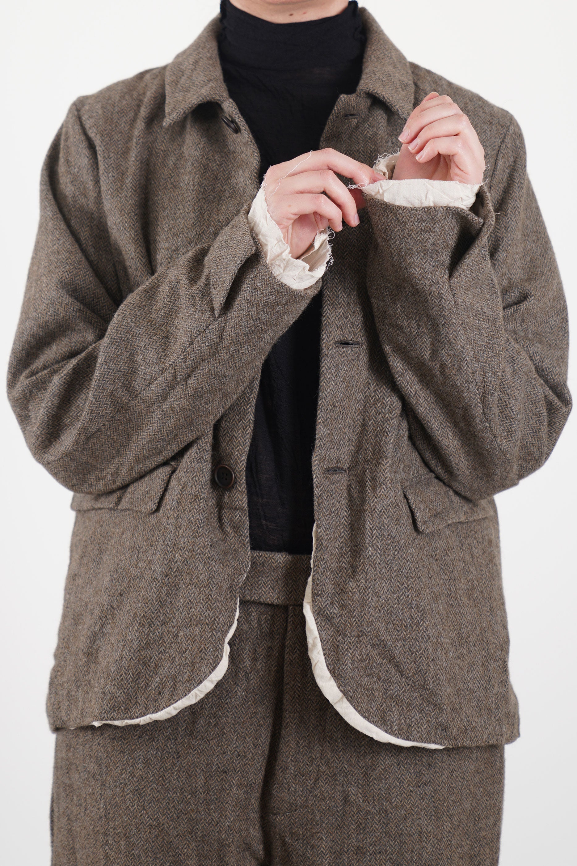 Front view of beige eco wool herringbone short jacket by Pas de Calais with button closure and curved hem