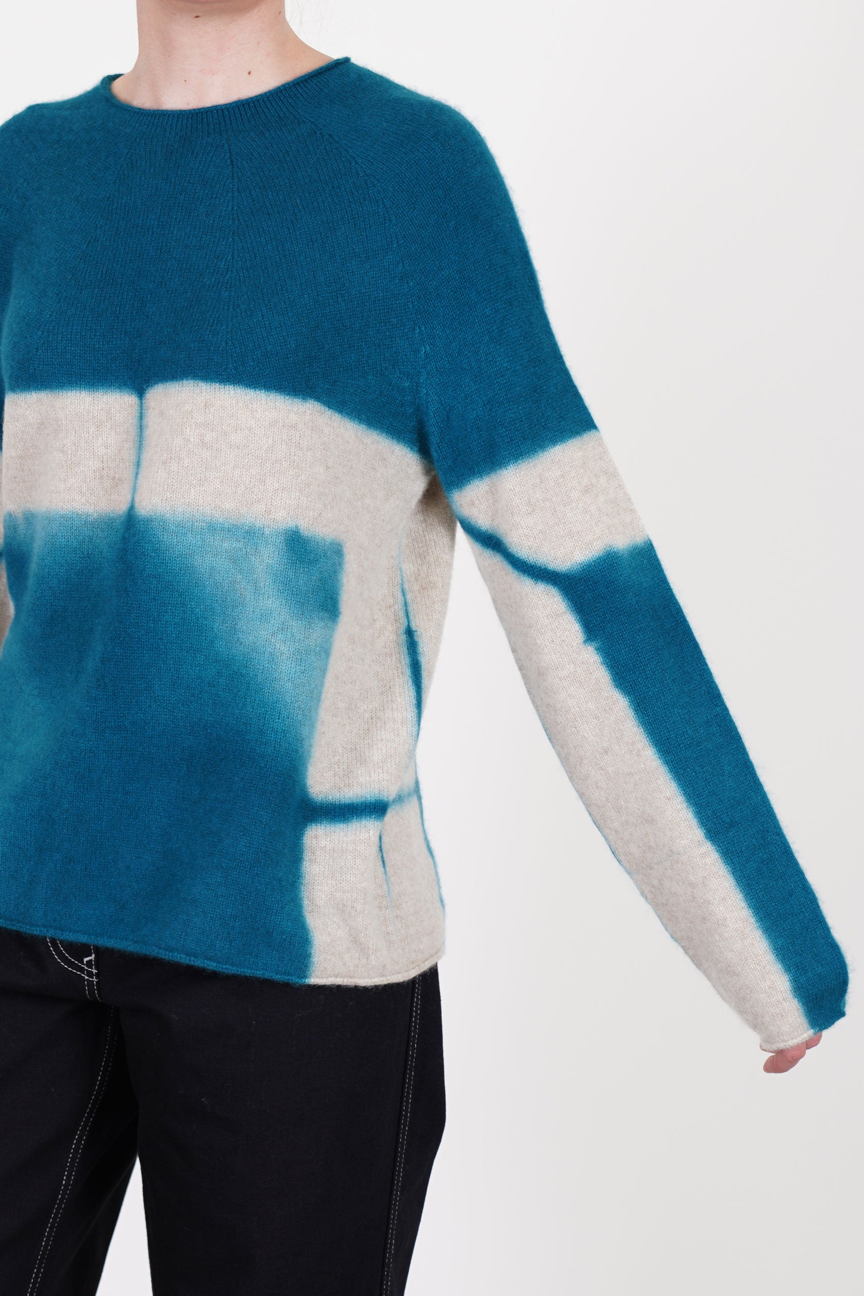 detail view of suzusan cashmere seamless pullover long dark teal sand slimmer fitted sleeves and rolled up details at the hemline and cuffs.